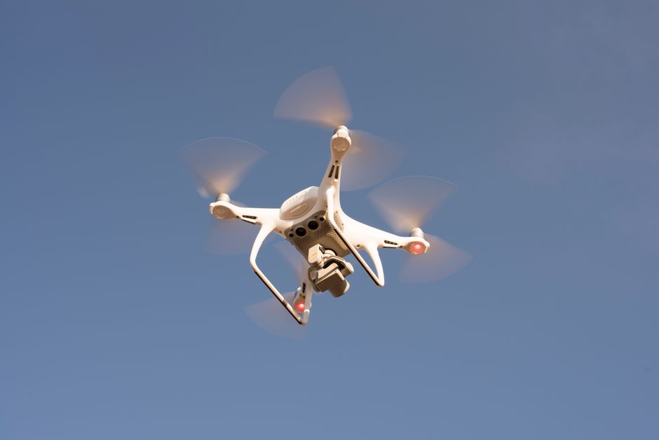 A drone equipped with LiDAR technology flying over a landscape for aerial surveillance and data collection.